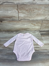 Flat lay of pale pink Oshkosh long-sleeve bodysuit showing scalloped Peter Pan collar and back keyhole on wood background