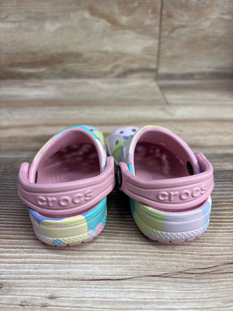 Rear view of Crocs Baya Patel Cloud Clogs showcasing pink heel straps and multicolor patterned uppers on a wood floor