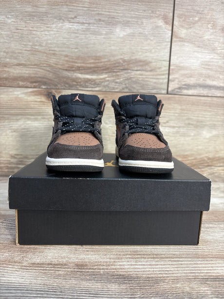 Pair of brown and black toddler Air Jordan sneakers with laces on a black shoe box