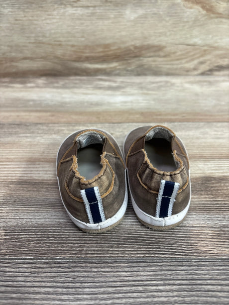 Pair of brown Robeez Lenny Loafer crib shoes with navy and white striped accents on a wood background