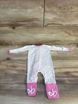 Pink polka dot baby onesie with flamingo print on feet, laid flat on wood floor