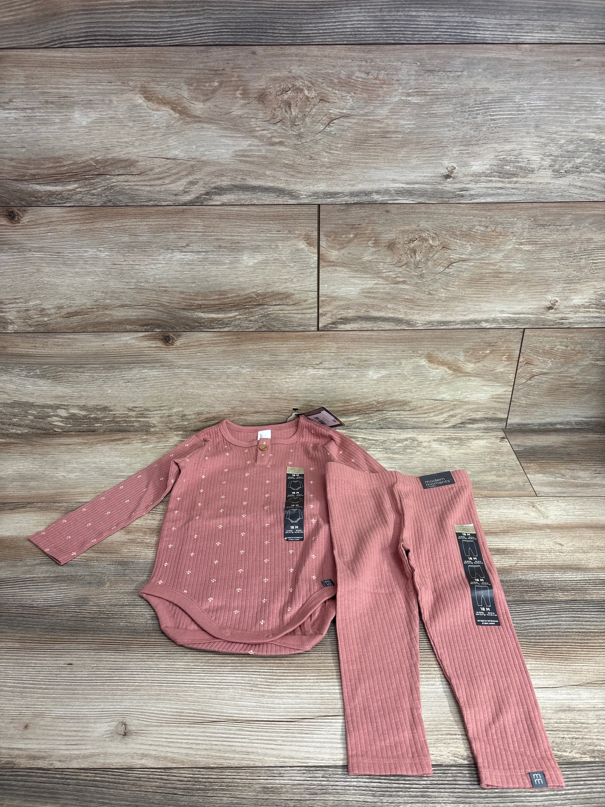 Flat lay of red ribbed 2-piece infant set long sleeve bodysuit with dot texture and wooden button, ribbed pants on light wood