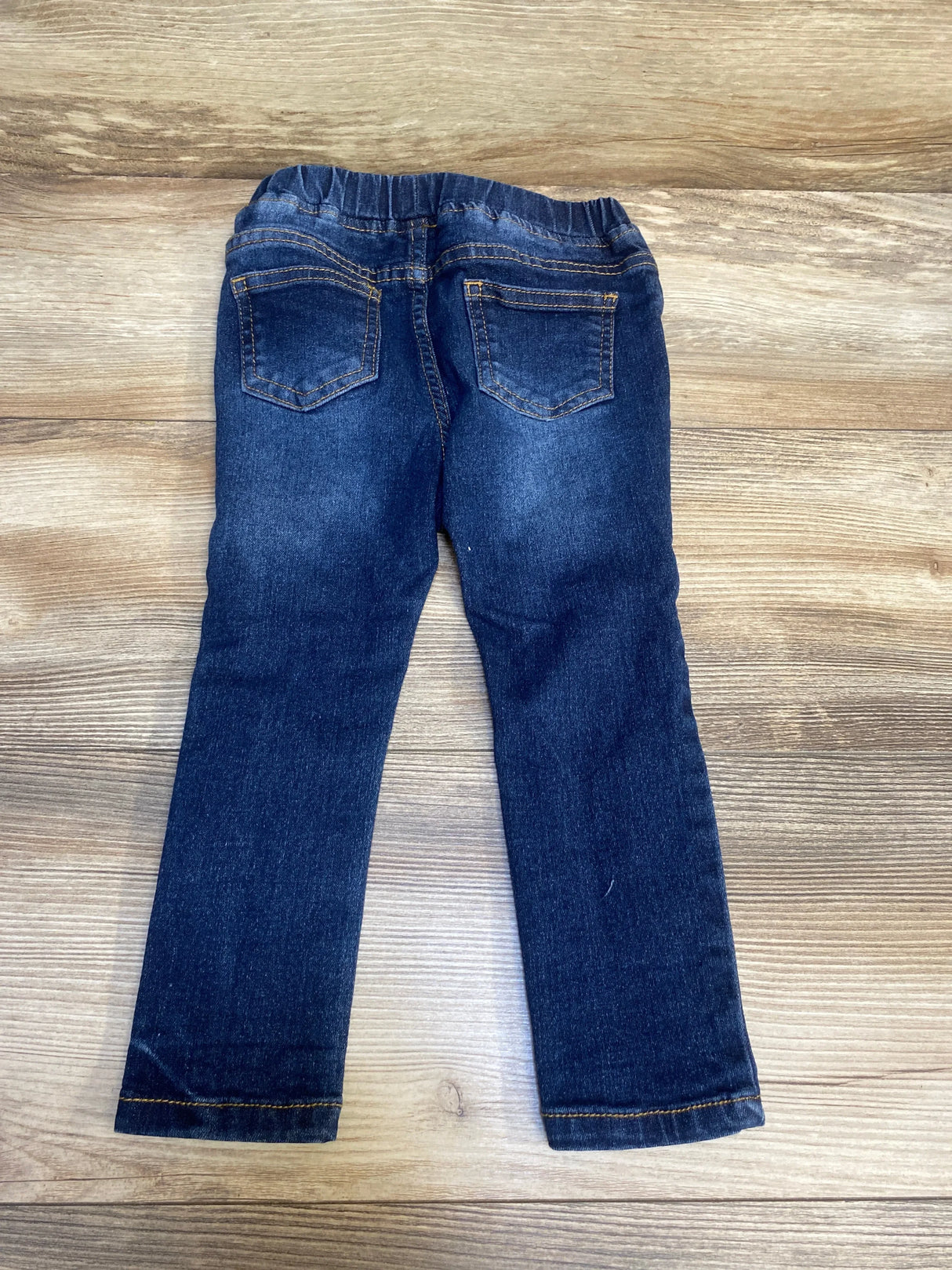 Dark wash kids jeans with elastic waistband and back pockets on wood background