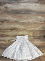 White ruffled girls dress with tag, displayed on wood floor, children's clothing