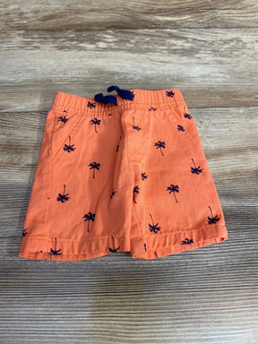 Top view of orange baby shorts 6-9m showing navy palm-tree print and elastic waist with navy drawstring on wood surface
