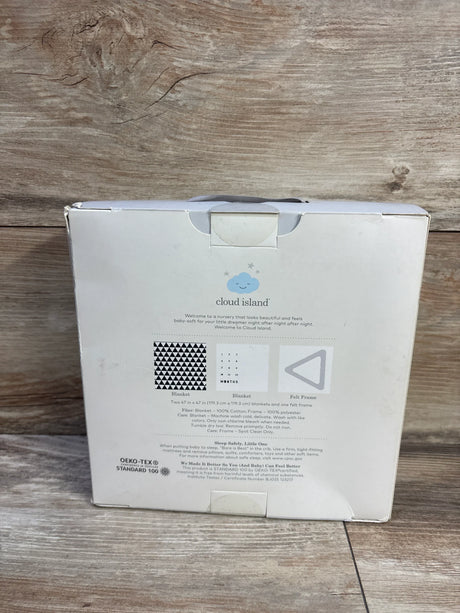 Front view of Cloud Island muslin blanket set box showing black triangle print sample and felt frame on wood floor