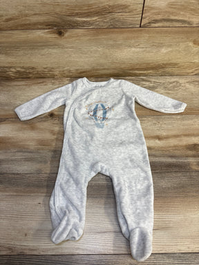 Light gray baby onesie with blue hot air balloon design laid on wooden floor