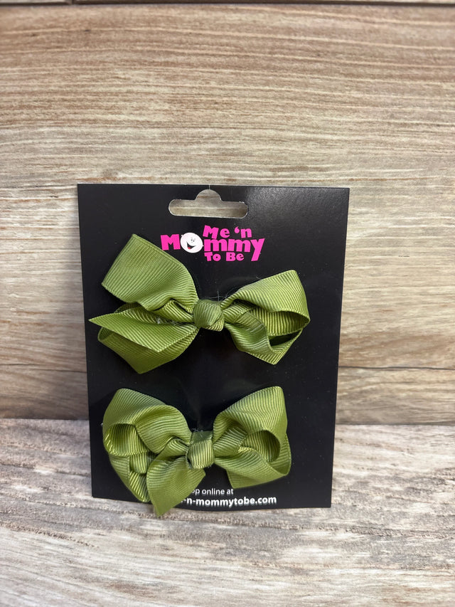Front view of two olive green grosgrain ribbon hair bows on black branded display card with wood-texture background