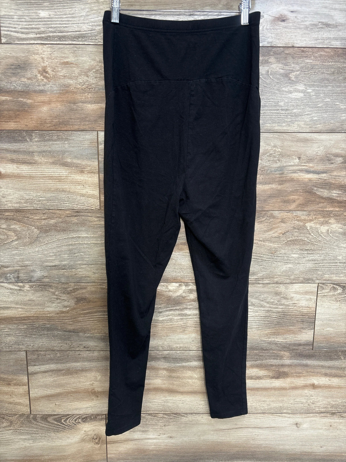 Front view of black Time and Tru maternity leggings with high-rise belly panel and full-length slim legs on wood plank background