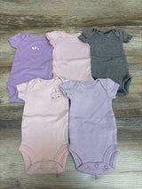 Top-down view of Carter’s five preemie bodysuits showcasing purple, pink, and striped designs on a wood surface