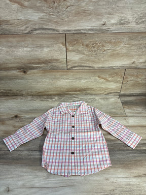 Pink and blue plaid button-up toddler shirt on wooden floor background