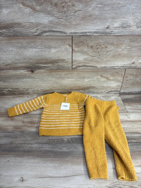 Yellow baby sweater and pants set with white stripes, laid on wood floor