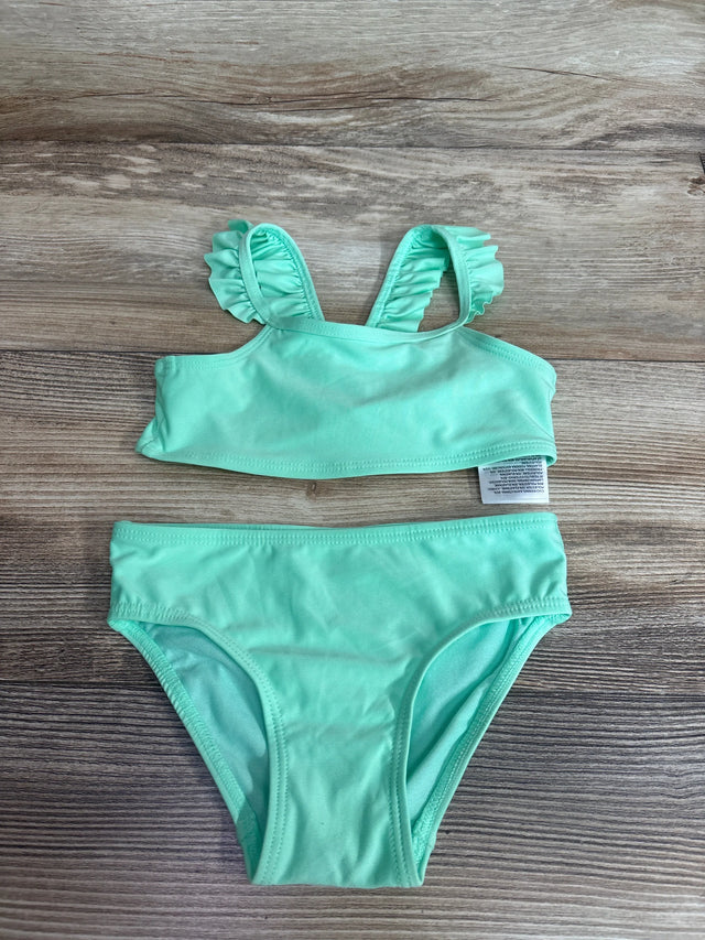 Flat lay of mint green toddler two-piece bikini showing ruffle-trimmed shoulder straps and matching briefs on wood background