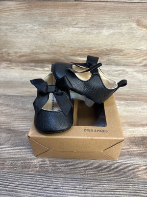 Black baby crib shoes with bows, soft sole, in box on wood floor