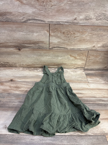 Front view of green Old Navy skirtall in size 5T showcasing shoulder straps, gathered waist, and tiered ruffled skirt on a wood floor
