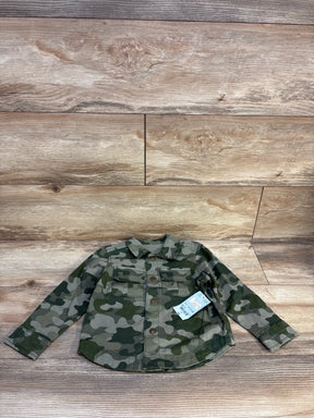 Kids camo print long sleeve shirt with buttons and front pockets, displayed on wood floor