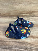 Three-quarter view of navy baby slip-on slippers showing colorful rocket and planet print, plush lining and heel pull tab on wood surface
