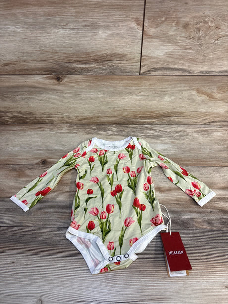 MILKBARN baby onesie with red tulip print, long sleeves, and snap closure on wood floor