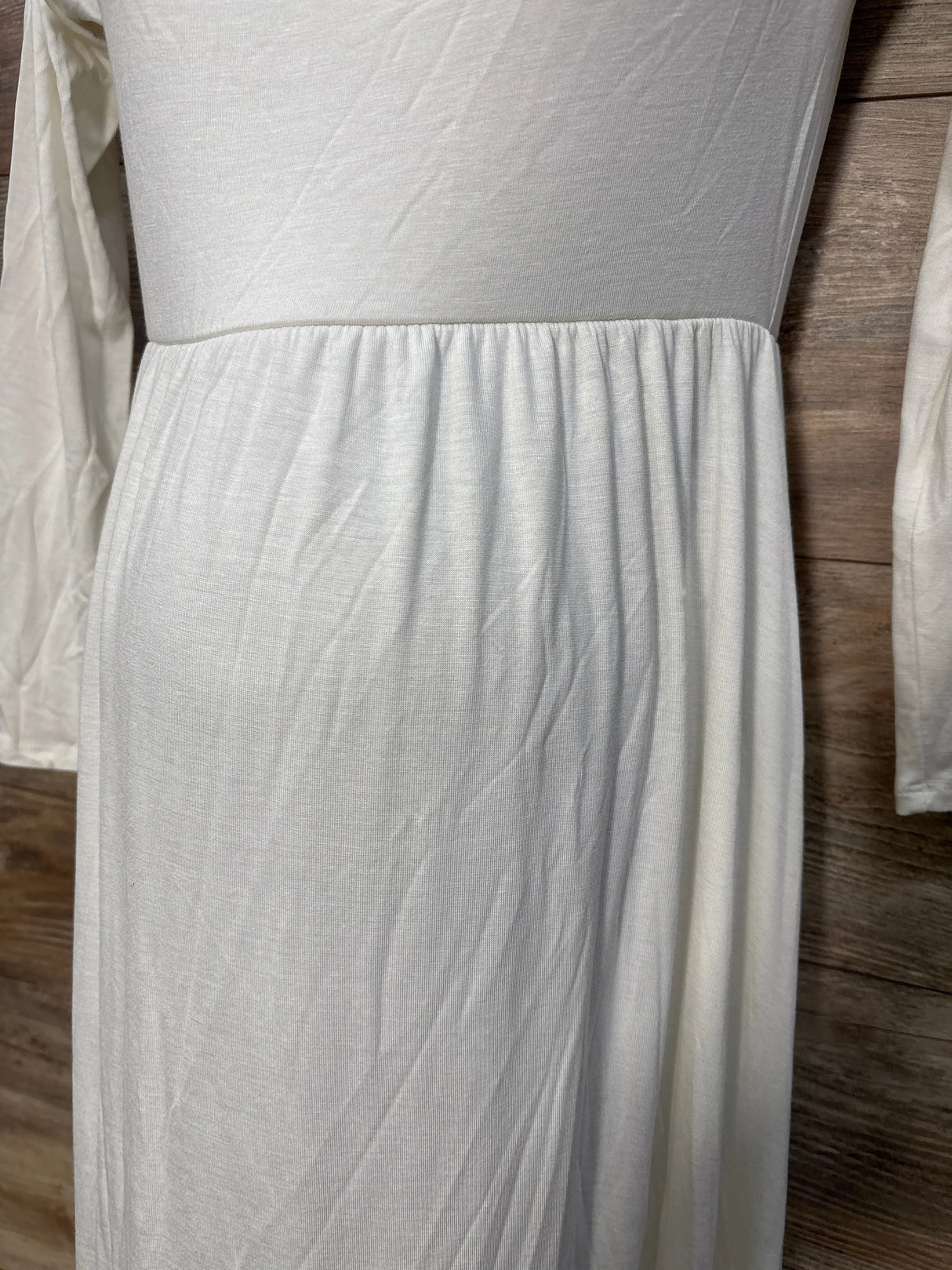 White long sleeve maternity dress with gathered waist, displayed on wood background