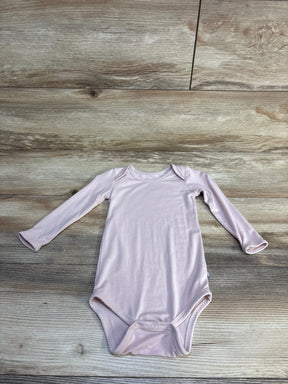 Light pink long sleeve baby bodysuit with snap closure on wooden floor