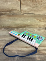 Angled view of VTech Bluey keytar showcasing white and black piano keys and colorful control buttons with navy strap on wood background