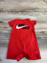 Top-down view of red baby shortie romper showcasing white Nike swoosh and JUST DO IT text on wood background