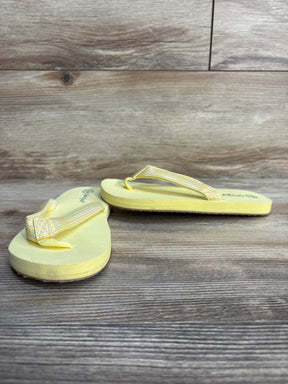 Yellow children's flip flops with textured straps on wood background