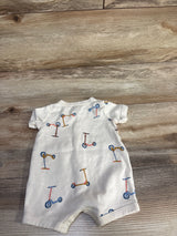 Back view of Carter's beige shortie romper showcasing multicolored scooter print and snap crotch closure on wood background