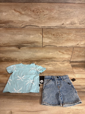 Flat lay of Volcom two-piece baby outfit showing light blue palm-tree T-shirt and jean shorts on wood floor