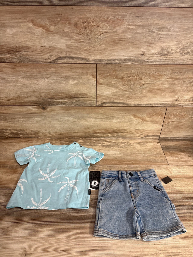 Flat lay of Volcom two-piece baby outfit showing light blue palm-tree T-shirt and jean shorts on wood floor