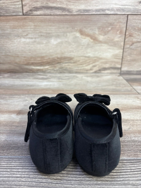 Rear view of Baby Gap velvet Mary Jane flats, black size 5C, showing bows and Velcro straps on light wood floor background