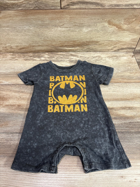 Front view of grey Batman shortie romper with yellow Batman logo and snap closures on a wood background