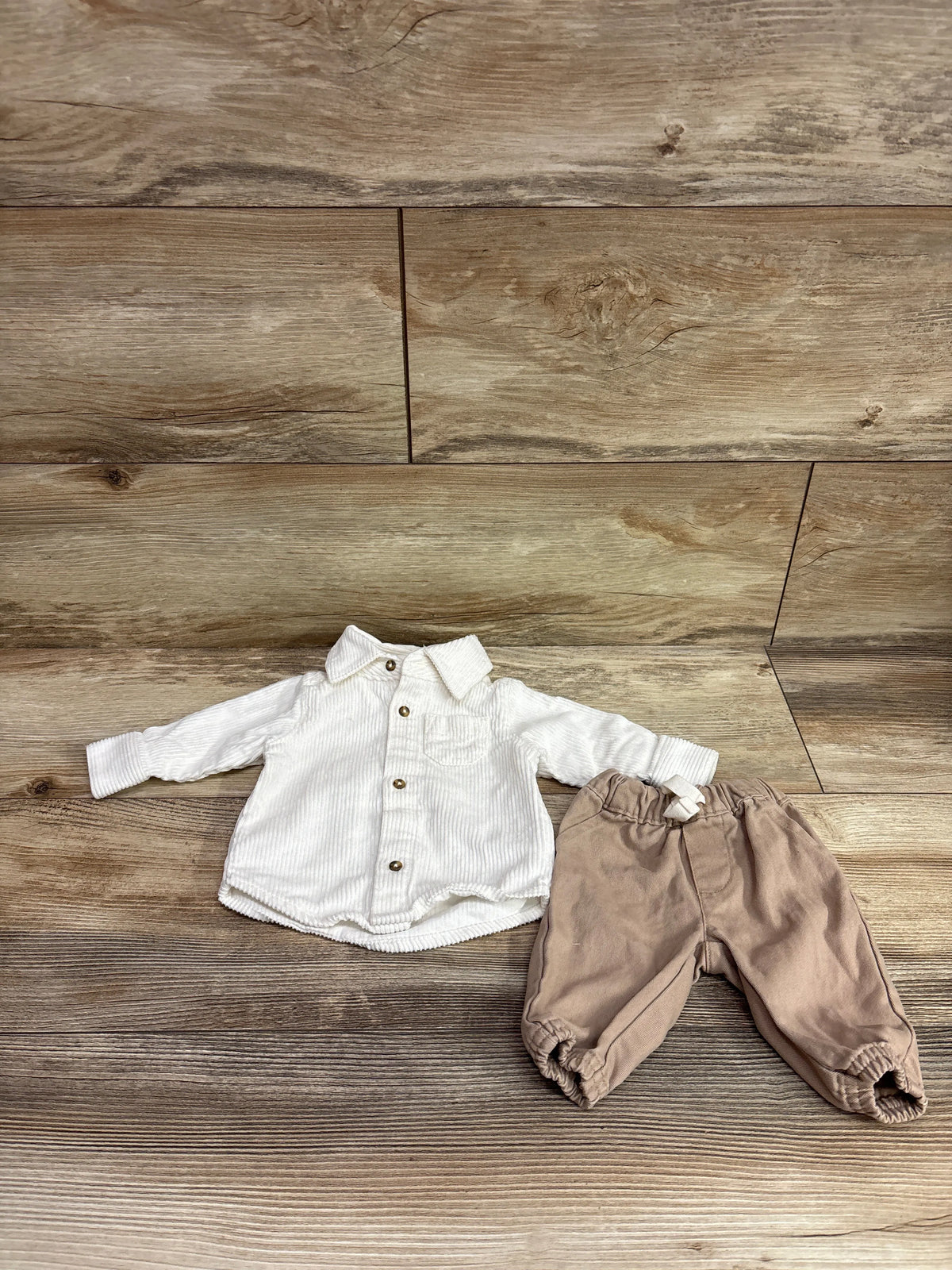 Flat lay of Just One You newborn corduroy shirt and pants set, showcasing a collared button-up shirt and elastic-cuff pants on wood