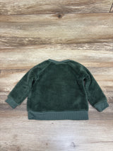 Back view of green Pekkle plush sweatshirt with ribbed cuffs and hem on a wood-grain background