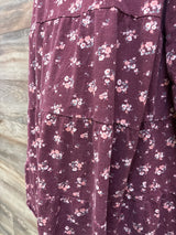 Close-up of a maroon tiered maternity dress with a small white and pink floral print.