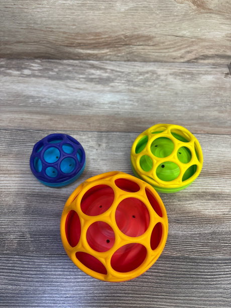 Top view of Bright Starts Oball stackable hollow balls (orange-red, yellow-green, blue) on wood background
