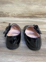 Black patent leather girls dress shoes with sparkly bow detail, displayed on wood floor