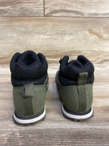 Back view of children's olive green and black hiking boots on wooden surface