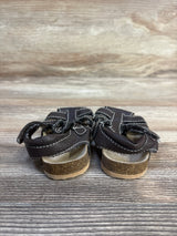 Brown toddler sandals with Velcro straps and cork soles on wood background