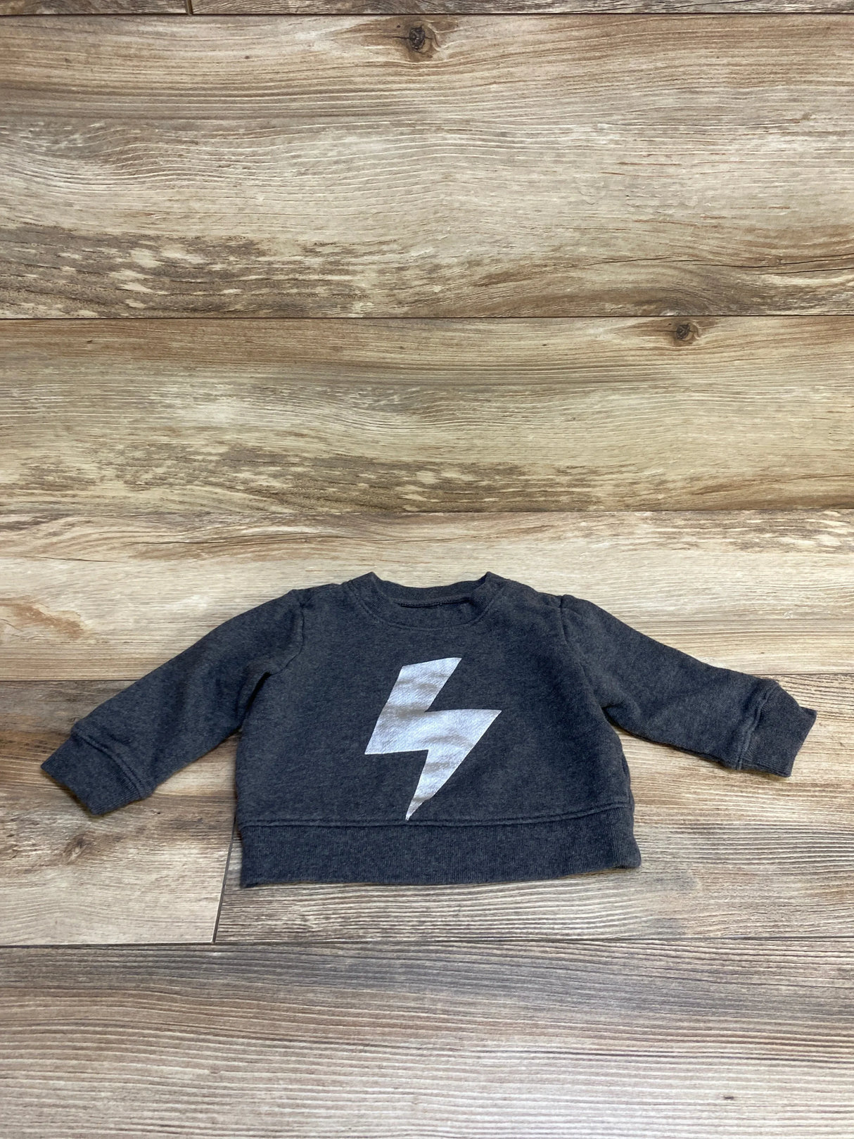 Dark gray toddler sweatshirt with silver lightning bolt graphic on wood floor background