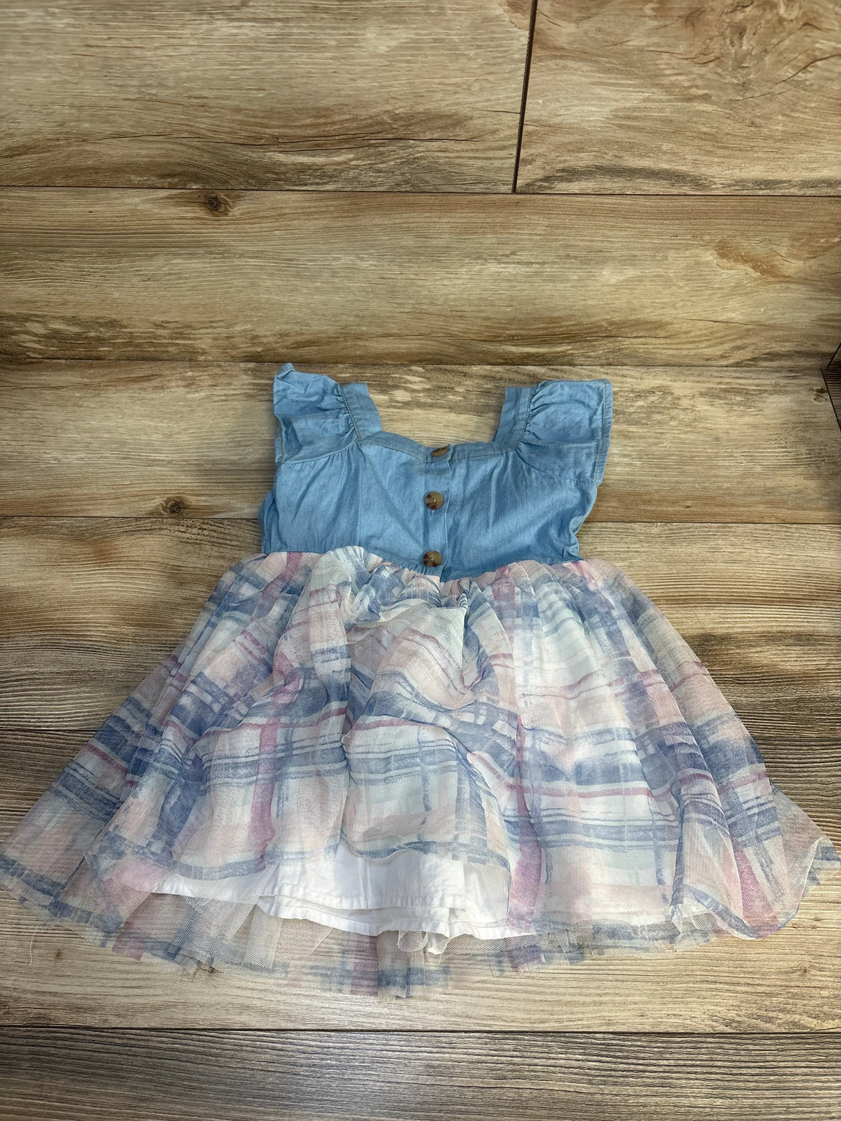 Girls sleeveless blue chambray dress with plaid tulle skirt on wood background