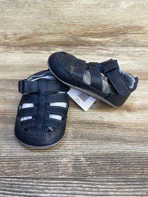 Front and side view of Just One You navy fisherman sandals size 4/5C 12-18M, woven toe straps and velcro tab on wood background