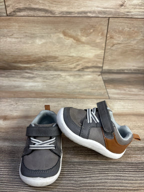 Front view of Munchkin by Stride Rite sneaker, grey and brown, velcro strap reading stride rite, white sole on wood floor