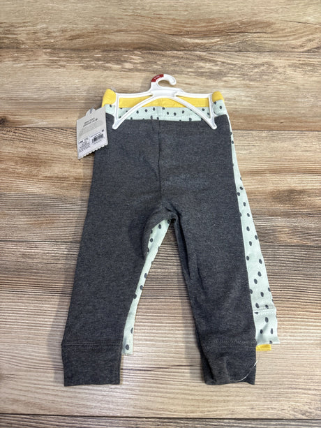 Set of three baby leggings on hanger, including gray, yellow, and polka dot patterns, displayed on wood surface