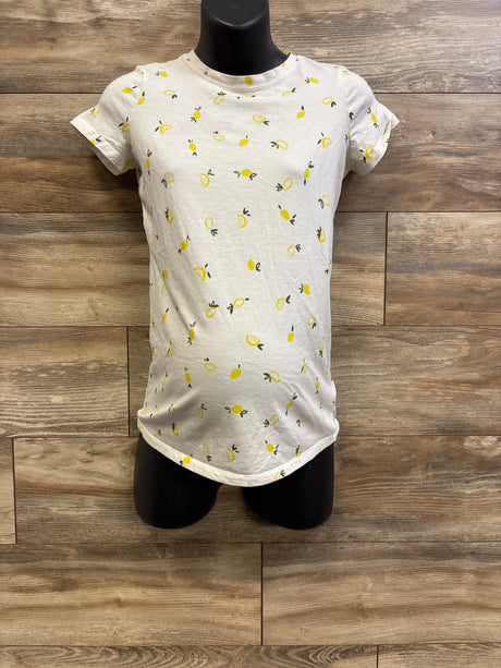 Front view of A Pea In The Pod maternity lemon-print shirt with curved hem and yellow lemon pattern against wood background