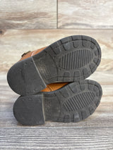Bottom of toddler brown boots with black rubber soles, size 5, lightly worn, wood background