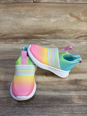 Angled view of toddler slip-on sneakers with ombre pink-to-yellow upper, striped elastic and white sole on wood background