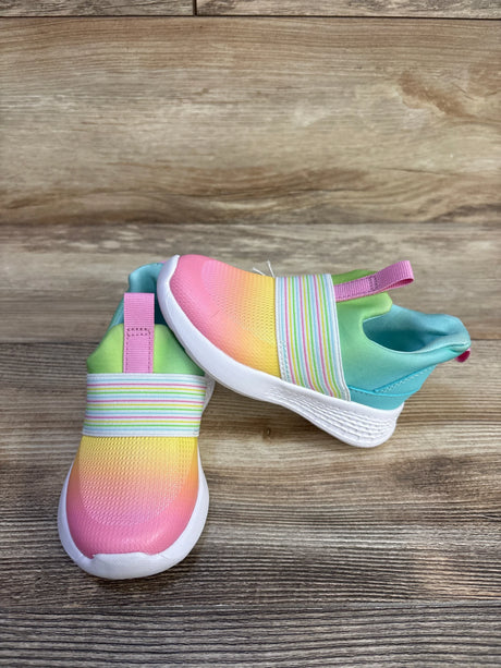 Angled view of toddler slip-on sneakers with ombre pink-to-yellow upper, striped elastic and white sole on wood background
