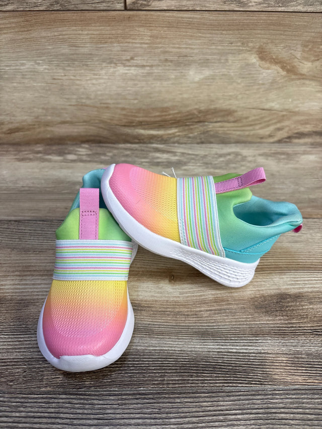 Angled view of toddler slip-on sneakers with ombre pink-to-yellow upper, striped elastic and white sole on wood background