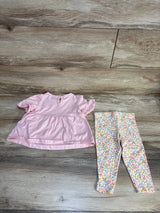 Pink baby top with ruffled sleeves and floral print leggings on wood floor